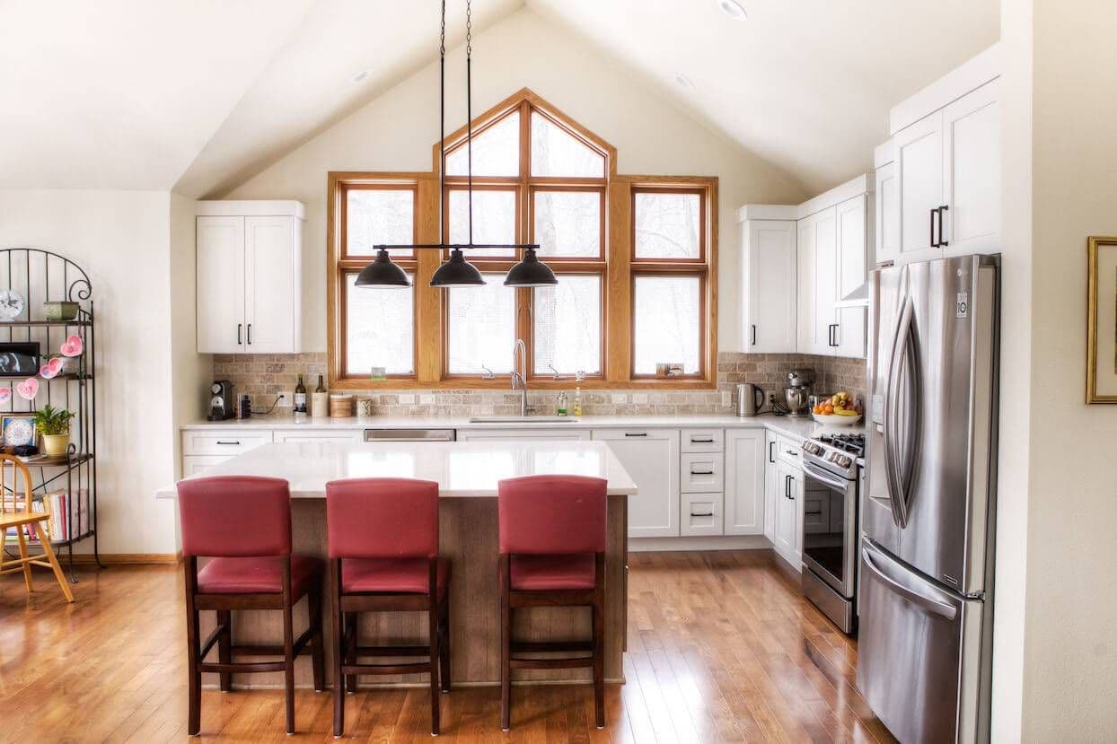 cabin-style kitchen with large windows and red chairs
