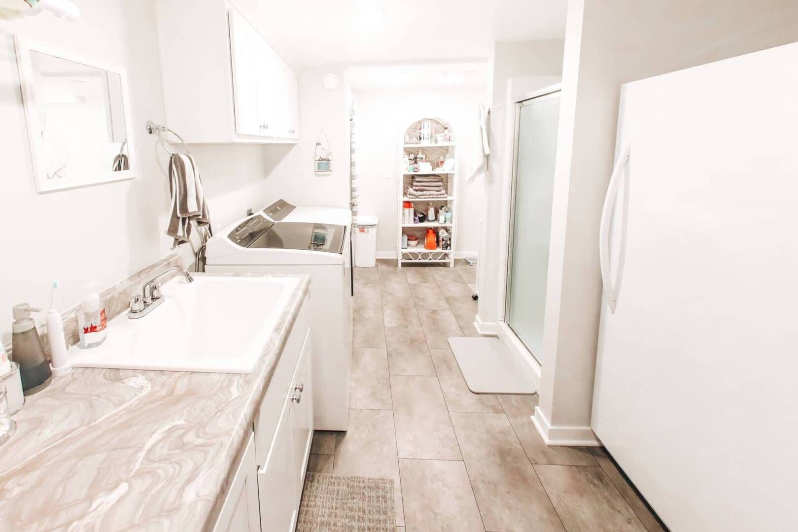 wide shot of complete laundry/bathroom all white with cream and gray marbling countertops/laminent