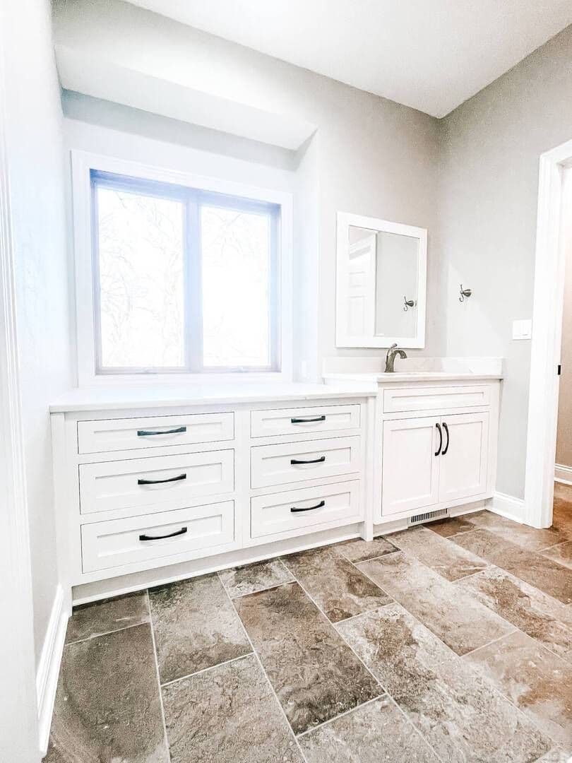Bathroom vanity with white cabinets and windows