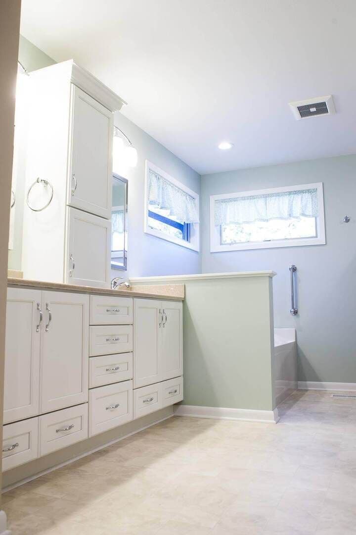 A photo of an extended bathroom including a spa and white cabinets.