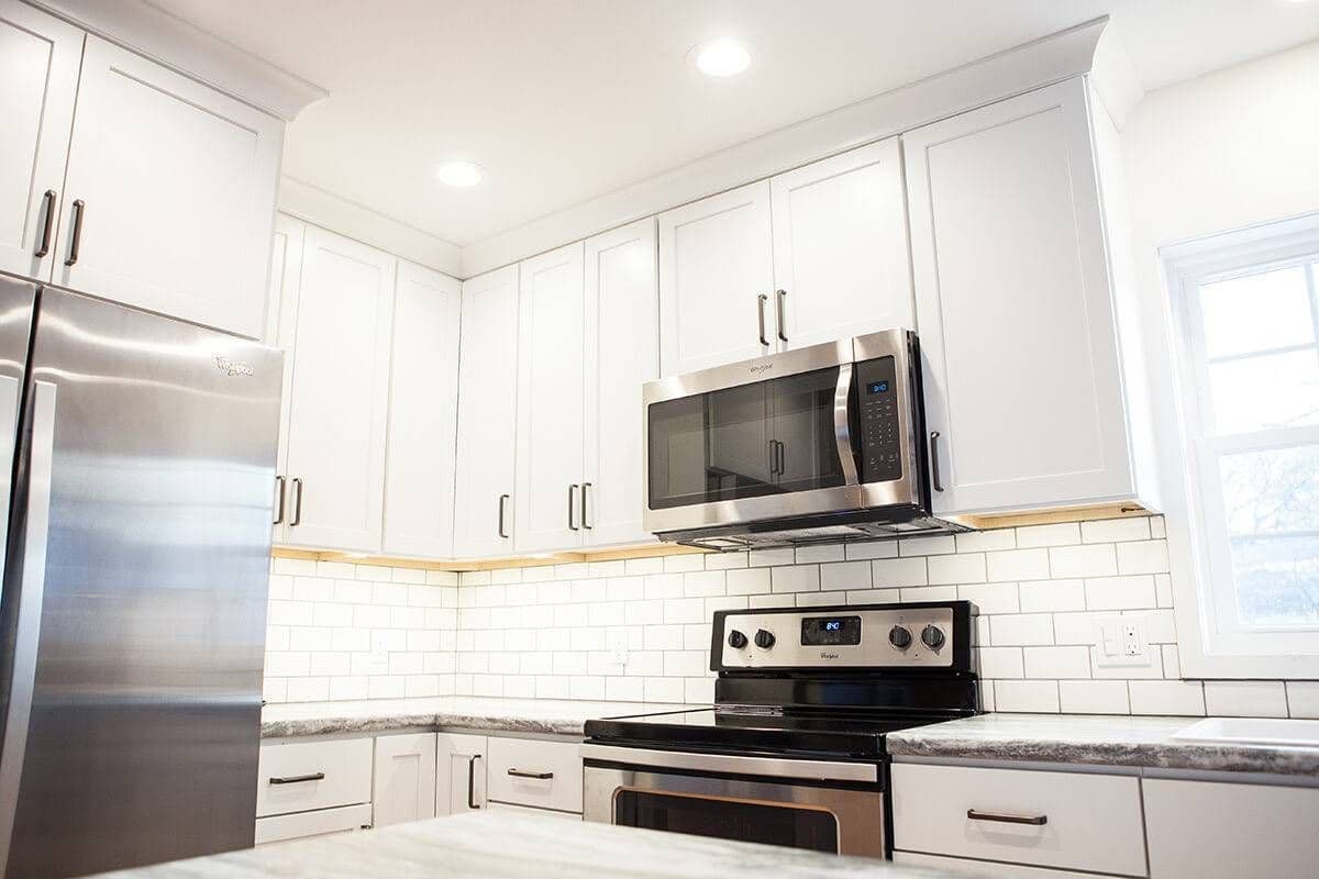 Kitchen with white cabinets. Black and stainless steel microwave and stove.