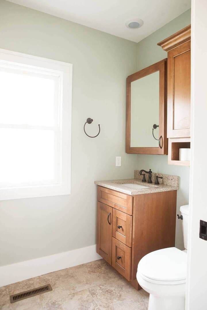 bathroom sink and mirror placed in the corner with a window letting in natural light