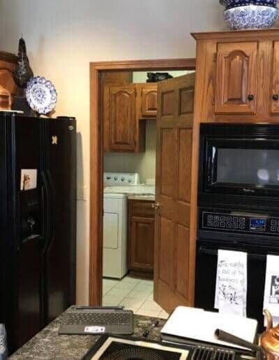 view of dark wood kitchen and black appliances with door on wall open to laundry room